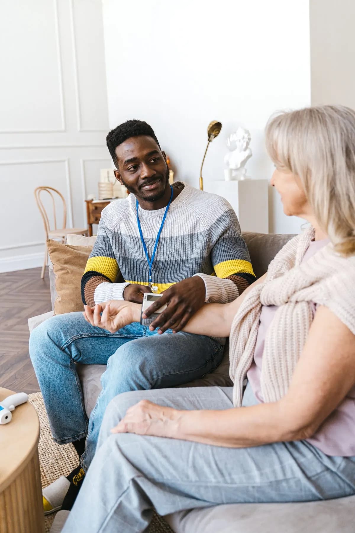 A care worker sitting with an older woman in her living room before a visit.