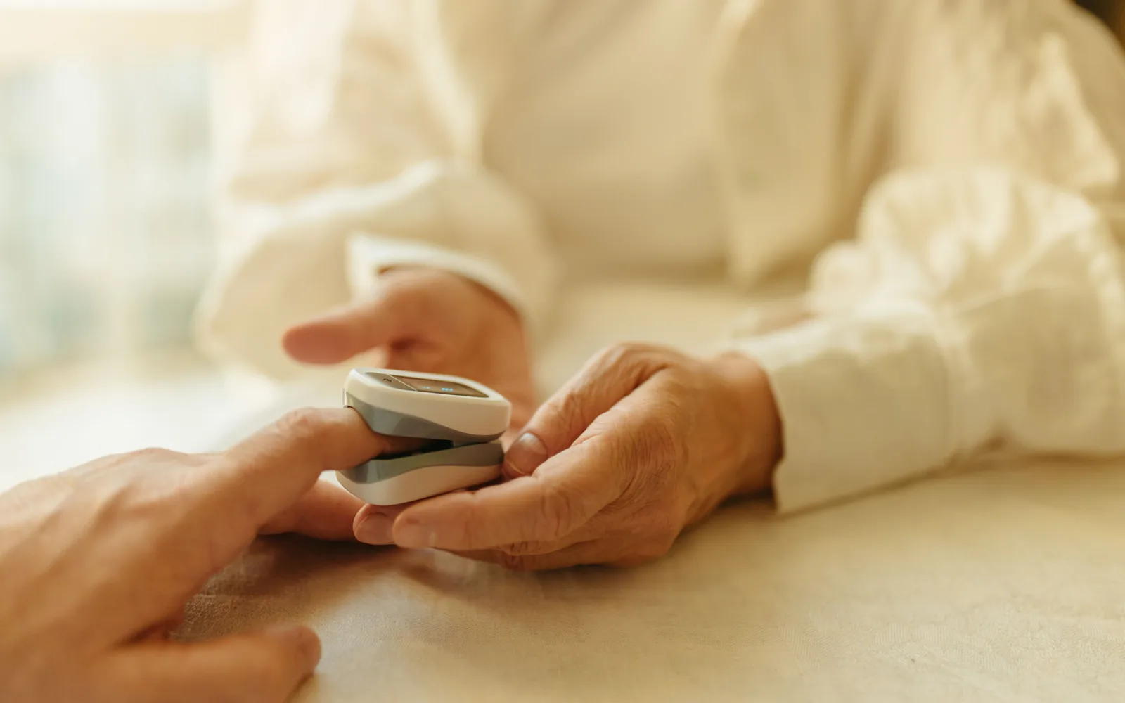 A person helping another use a fingertip health device