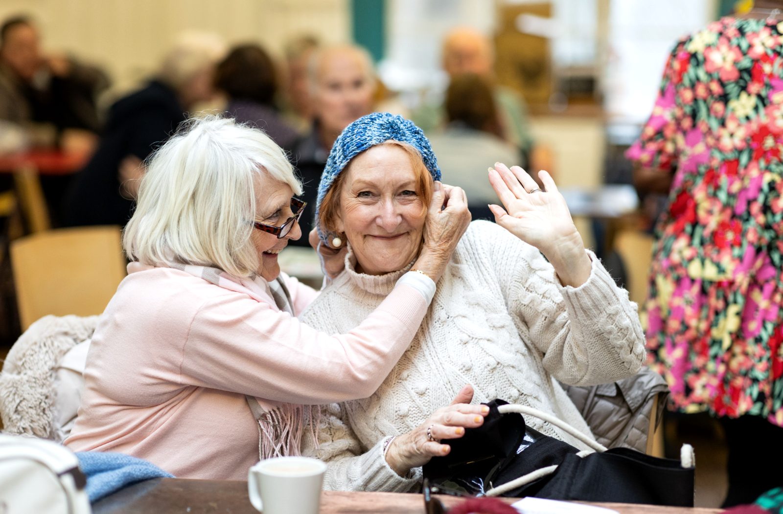 Two residents laughing together over coffee at a UK care home