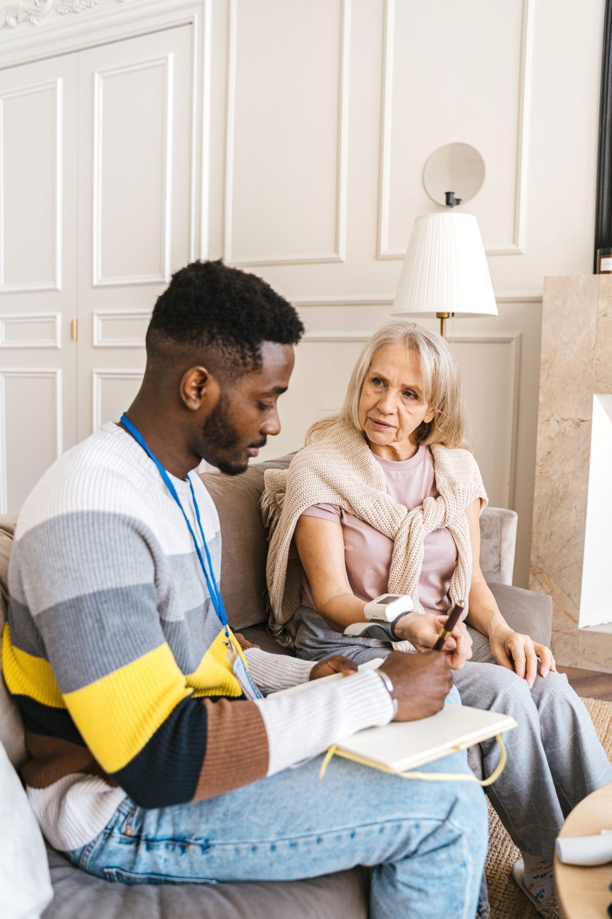 Carer taking blood pressure and notes during a home care visit